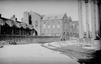 View from S showing part of SSW and ESE fronts of extensions of S block of mill with part of houses on left and gasholder on right