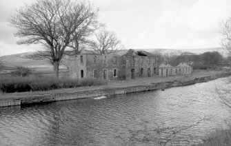 General view from SSE showing remains of SSW and ESE fronts of stables with cottages on right