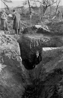 Photograph of second Antonine ditch at Mumrills Roman Fort showing Sir George MacDonald in earlier deeper ditch coalescing with it.
Copied from A O Curle photograph album MS/28/461.