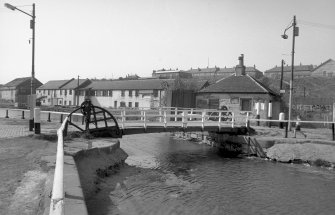 View from SSE showing ESE front of bridge with bridgekeeper's cottages in right background and workshops in left background