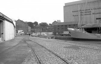 View from SSW showing part of boat in harbour with part of warehouse on left, part of grain wharf warehouses on right and part of grain silo in background