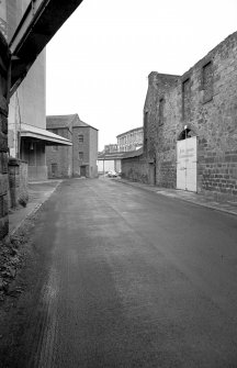 View looking SSW showing ESE front of warehouse with remains of warehouse on right and part of grain wharf warehouses in background