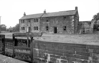 View from SE showing SSE and ENE fronts of lockeeper's house and stables with remains of E lockgates in foreground