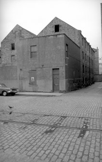 View from N showing NNE and WNW fronts of number 6 with warehouse in background