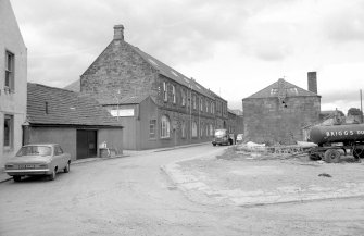 View from SE showing part of SSE and ENE fronts of mill with workshop on right and part of public house on left.