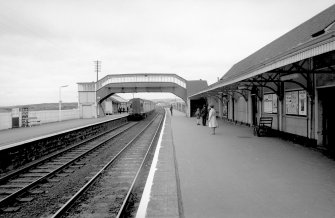 Scanned image of view looking NNE showing SSW front of footbridge with up platform building in background and part of down platform building on right