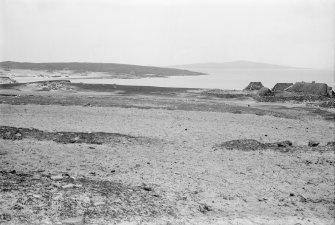 View of Cladh Manach disused burial ground at NF 8558 8050 showing blackhouses, from the SW 
