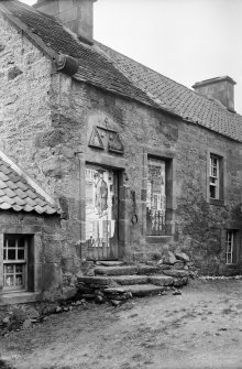 View of front of building, with jougs to right of door.
