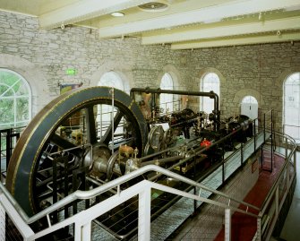 New Lanark: interior. View from S within engine house showing steam engine.  Similar to the original engine, this is a 250hp twin-tandem compound mill engine by Petrie of Rochdale (1912) re-located from Philiphaugh Mill near Selkirk by the New Lanark Conservation Trust