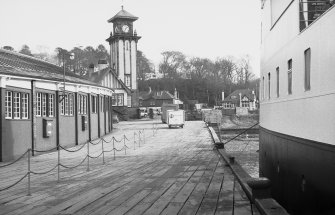General view from W showing covered walk-way, clock-tower and pier