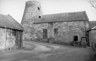 View from W showing tower and WNW front of mill block with part of ancillary building in foreground