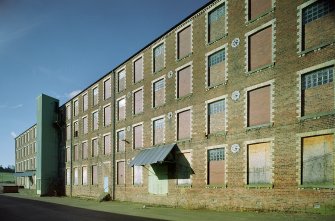 Digital image of a general view from ENE of SE side of four-storeyed Mule Spinning Mill (buildings B4, B5 and B6), showing polychrome brick exterior and external hoist tower