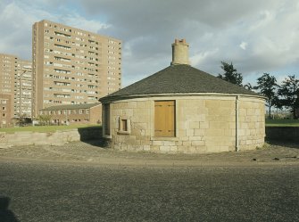 View from WNW showing tollhouse with tower blocks in background