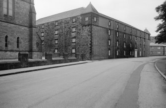 View from SSE showing SSW and ESE fronts of distillery with part of church in foreground