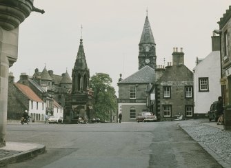 Fife, Falkland. General view from WSW showing fountain with (left to right) The Saddlers, Post Office, St Andrew House, Palace, Town House and hotel in background