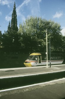 View from S showing Edinburgh - Aberdeen train at platform with Scott Monument in background