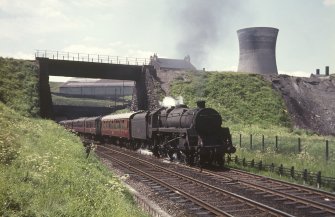 View from NNE showing Glasgow - Aberdeen train passing below Pinkston Road with power station cooling tower in background
