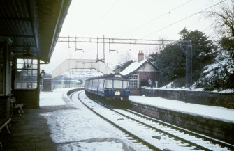 View from WSW showing Glasgow - Neilston train entering station with footbridge in background