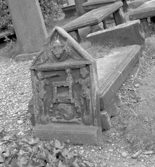 View of tombstone to John Michie's children 1738 depicting winged soul in pediment, St Mary's Church burial ground, Banff. Two standing figures in panel below, one playing trumpet and the other holding hour-glass. Inserted between figures is death bed, skull and bone.