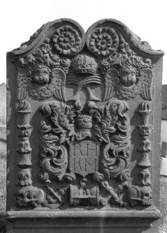 Errol Old Parish Churches, Errol Churchyard.
General view of gravestone of Margaret Hill, 1754. Rosettes, crown over crossed palm fronds and vine, double winged souls and pair of double torches. Foliate crest Insc: 'R.H K.M'. Emblems of mortality linked by ribband. (skulls, arrows of Death, hourglass and crossed bones).
Digital image of A 37033 PO