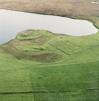 Oblique aerial view centred on the remains of the broch with the remains of the buildings and burnt mound adjacent, taken from the ENE.