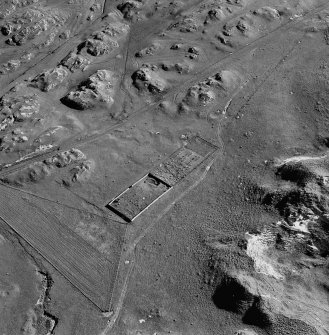 Oblique aerial view of Killunaig church centred on the remains of a church and a cemetery, taken from the NNW.