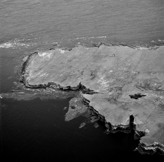 Stroma, oblique aerial view, taken from the W, centred on Bught o' Camm promotory fort and, showing Nethertown township in the centre right of the photograph.