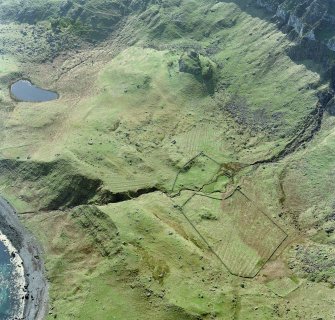 Oblique aerial view centred on the remains of the farmstead, shieling-huts and rig with fort adjacent, taken from the NE.
