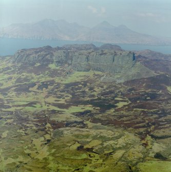 Oblique aerial view centred on the remains of the An Sgurr fort with Rum in the background, taken from the SE.