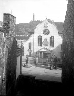 Elevated view of Canongate Church, Edinburgh, from south, with Burgh Cross and Home Fountain in front, and Nelson's Monument and National Monument behind.