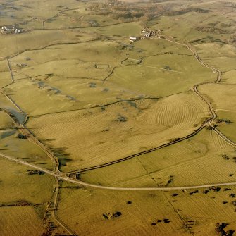 Oblique aerial view centred on the remains of rig with church, burial ground, homestead moat and building adjacent, taken from the ESE.