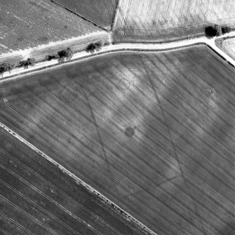 Oblique aerial view centred on the cropmarks of square and round barrows, a probable roundhouse and the central portion of a ditch-defined cursus, taken from the ENE.