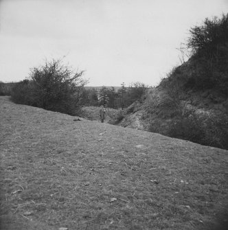 View of a man (R.J.C. Atkinson?) standing above the ditch of the motte.