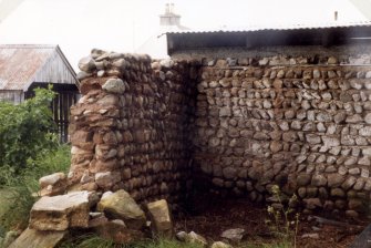 View of W wall of boulder and clay built outbuilding from SW.