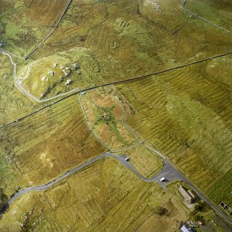 Oblique aerial view centred on the remains of the stone circle, chambered cairn and stone alignments with the township and lazy beds adjacent, taken from the NE.