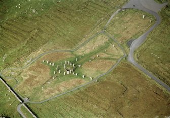 Oblique aerial view centred on the remains of the stone circle, stone alignments and chambered cairn, taken from the SE.