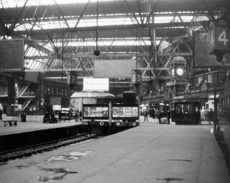 Scanned image of view looking north showing general concourse area including ends of platforms 2, 3 and 4 at buffer stops, refreshment rooms, booking hall and clock.