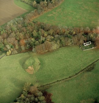 Oblique aerial view centred on the remains of the motte with the church and burial-ground adjacent, taken from the SW.