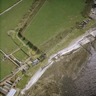 Oblique aerial view centred on the remains of the castle with the farmsteading adjacent, taken from the N.