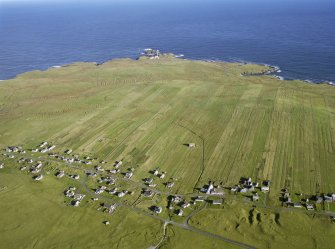 Oblique aerial view centred on St Moluag's chapel and township with lazy beds at Eoropie, Lewis and Butt of Lewis lighthouse adjacent, taken from the S.