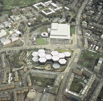 Oblique aerial view centred on the offices with the swimming pool, school, burial ground, halls of residence and church adjacent, taken from the NW.