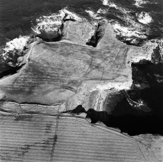 Oblique aerial view of the remains of the fort, chapel, harbour and rig, St john's Point, taken from the S.