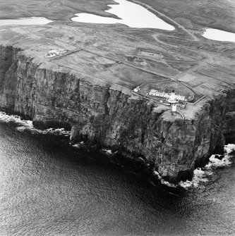 General oblique aerial view looking over the cliffs at Easter Head, Dunnet, to the lighthouse, radar station and the remains of the cairn, taken from the N.