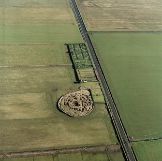 Oblique aerial view centred on the remains of Kirk Tofts broch, Keiss, with the memorial and graveyard adjacent, taken from the SW.