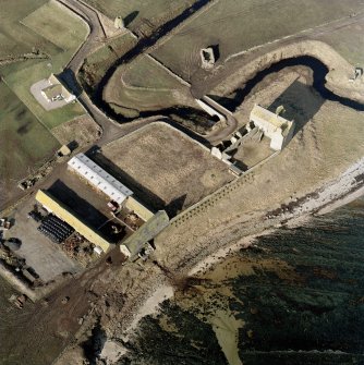 Oblique aerial view of Freswick castle, bridge, farmsteading and the remains of the mausoleum, dovecot and anti-tank blocks, taken from the E.