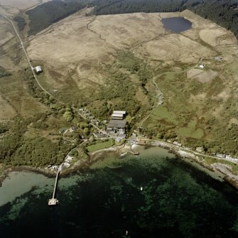 Oblique aerial view centred on the distillery, hotel and piers, taken from the NE.