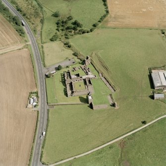 Oblique aerial view centred on the remains of the abbey and the doocot and cottage, taken from the W.