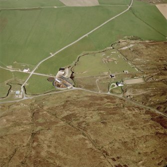 Oblique aerial view centred on the farmhouse, farmsteading, engine house and hut, taken from the SE.