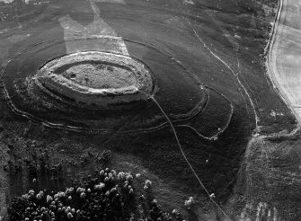 Oblique aerial view centred on the cropmarks of roundhouses  and a rectangular enclosure within the White Caterthun fort with the remains of an unenclosed settlement adjacent, looking to the NW.