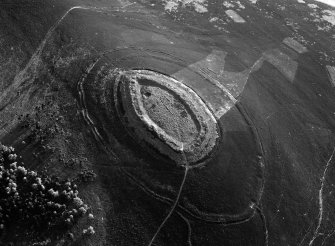 Oblique aerial view centred on the cropmarks of roundhouses  and a rectangular enclosure within the White Caterthun fort with the remains of an unenclosed settlement adjacent, looking to the S.
